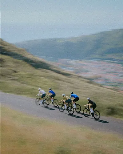 A group of cyclists biking up a green mountain